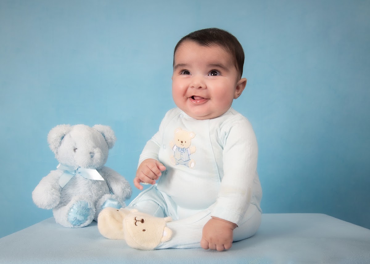 Smiling baby milestone portrait with a teddy bear