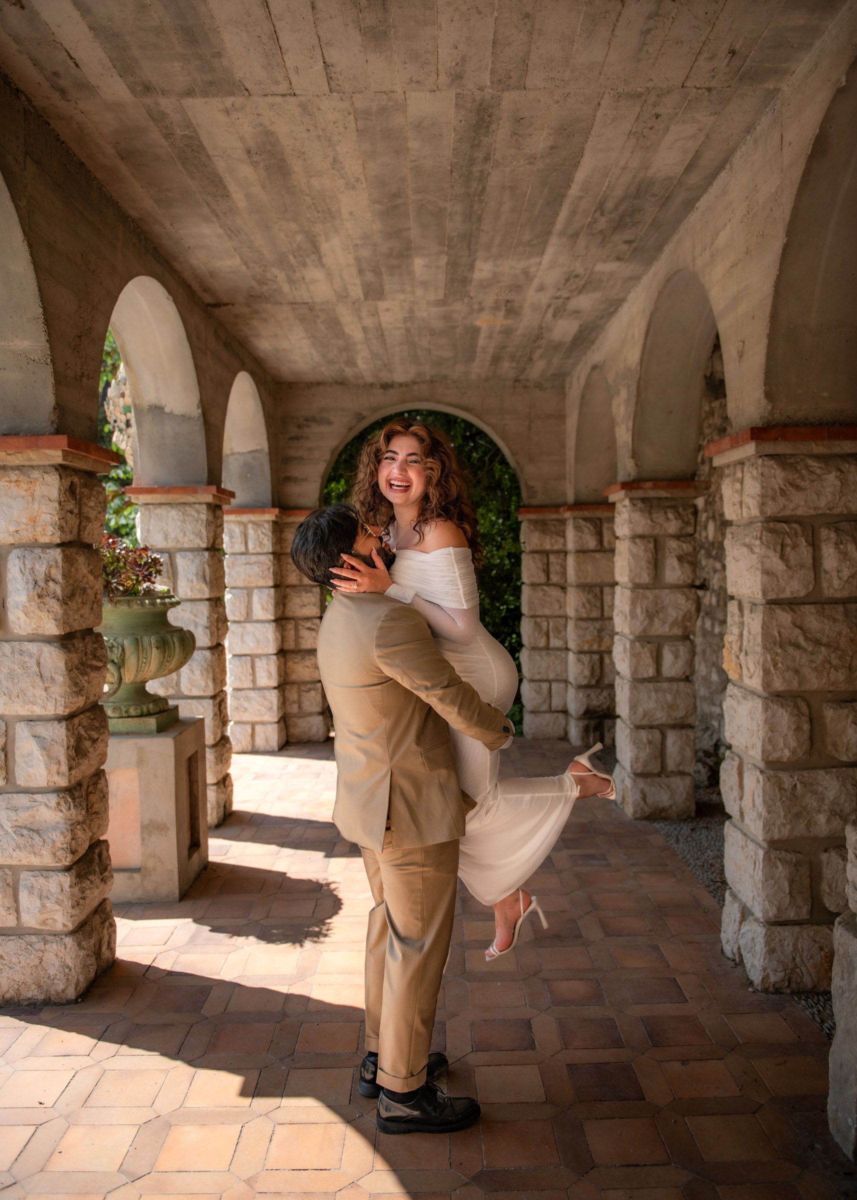 Couple embracing beneath a stone arcade