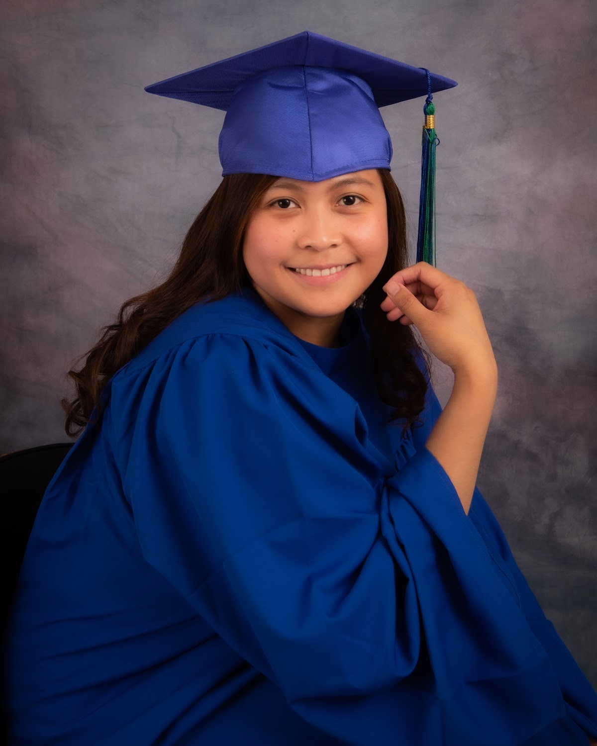 Graduate portrait seated in a blue gown