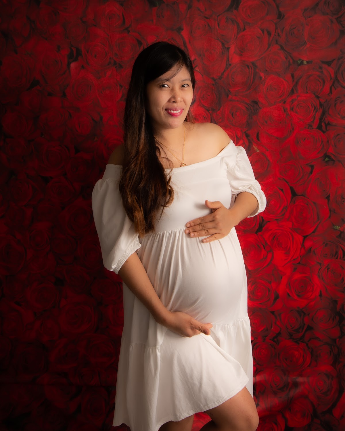 Maternity portrait in a white dress with red roses