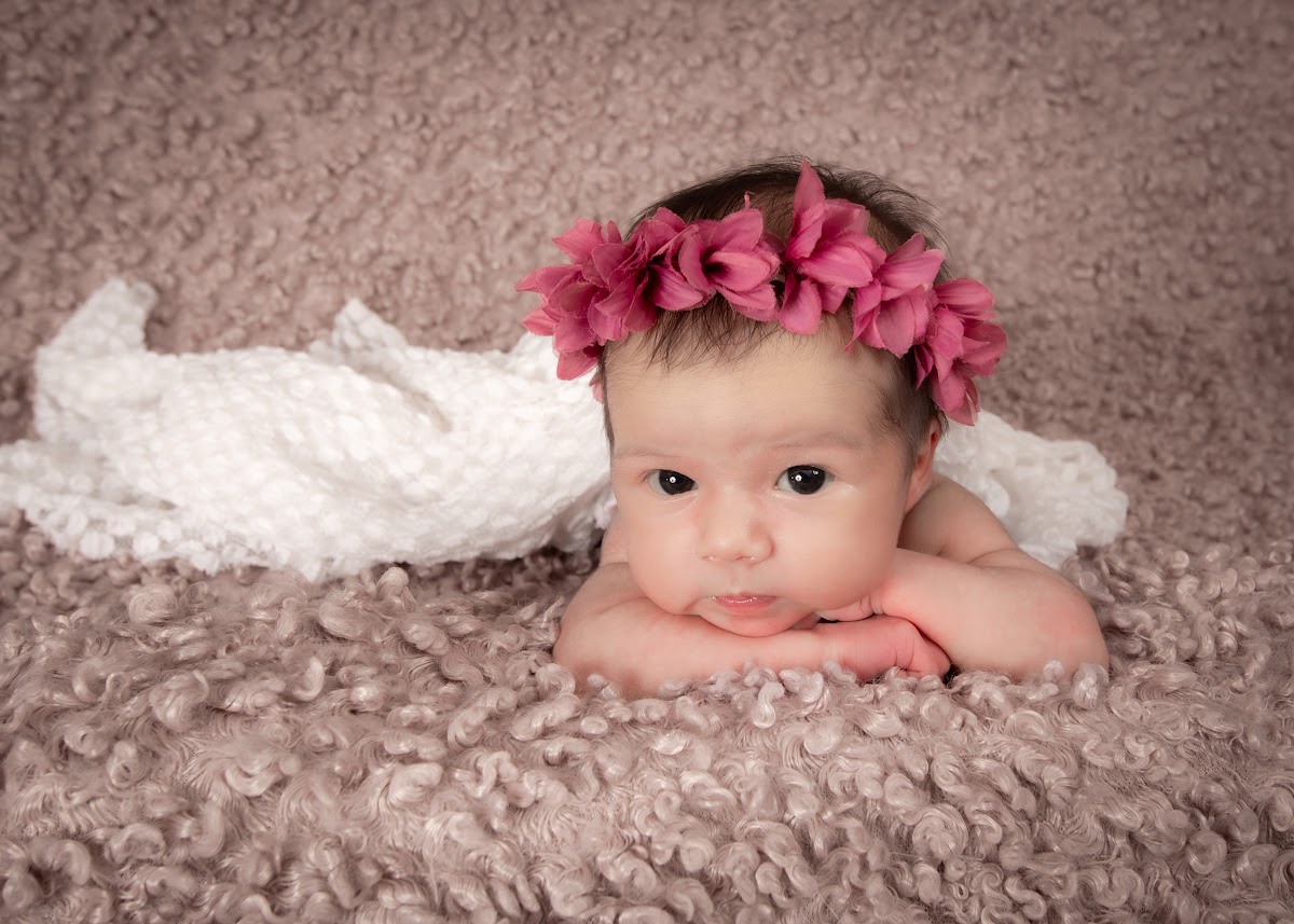 Awake newborn baby portrait with a pink flower